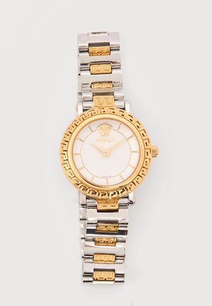 Montre-bracelet Versace en or et argent avec logo Méduse, cadran rond et maillons à motif sur fond blanc.