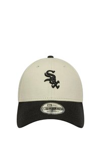 Cappellino da baseball beige con visiera nera, dotato di un logo ricamato nero "Sox" sulla parte anteriore e un'etichetta circolare che mostra informazioni su taglia e stile.
