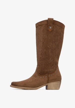 Bota alta hasta la rodilla de ante marrón con patrón floral recortado, detalles con tachuelas, bordado decorativo y diseño de tacón apilado.