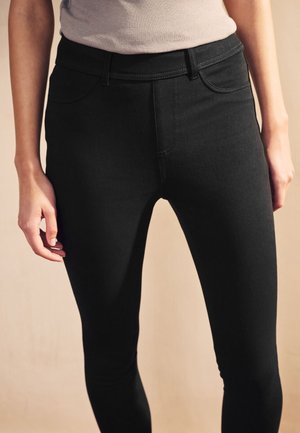 Schwarze Denim-Leggings mit figurbetontem Design, einem hohen Bund, Standardtaschen und dezenten Nähten entlang der Nähte.