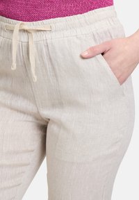 Lichtbeige linnen broek met een koordsluiting in de taille en zijzakken, met een structuurstof en een relaxte pasvorm.
