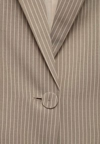 Blazer beige à fines rayures avec revers crantés et une fermeture unique par bouton recouvert au centre devant.