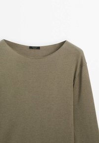 Pull vert olive à manches longues avec un large décolleté, confectionné dans un tissu doux et texturé. Design simple avec des détails de couture minimalistes.