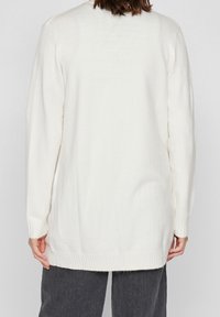 Cardigan a maniche lunghe color crema in maglia, con orlo e polsini a coste. Il retro presenta un taglio dritto e un tessuto morbido e testurizzato.