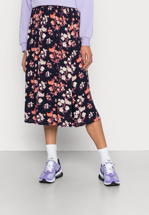 Saia floral de comprimento médio com fundo azul marinho, adornada com flores rosas e brancas. Usada com ténis lilás claros e meias brancas.