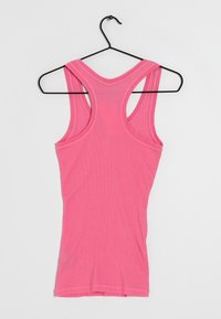 Růžový top na ramínka s racerback designem, vyrobený z měkké látky, s úzkými pásky a hladkým povrchem, zavěšený na černém háčku.