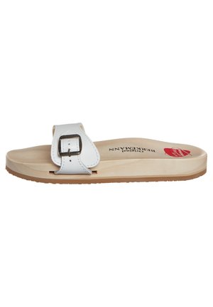 White slide sandal with wooden sole, adjustable white leather strap with metal buckle, and red logo on footbed.