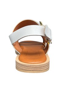 Sandale en cuir argenté avec une large bride, talon ouvert et semelle intérieure rembourrée couleur tan. Elle présente une boucle dorée pour un ajustement réglable sur le côté.