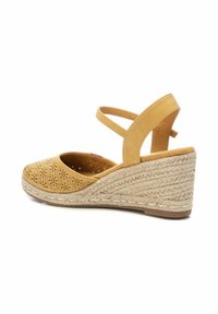 Sandali con tacco a cuneo dal superiore perforato color marrone chiaro, con cinturino incrociato e suola in iuta intrecciata. Il design presenta una punta arrotondata e una soletta imbottita.