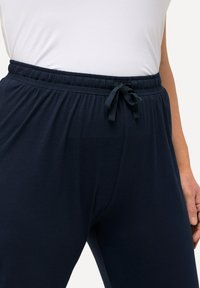 Marina blå sweatpants med elastisk midja och justerbar dragsko, tillverkade av mjukt tyg, med avslappnad passform och utan synliga mönster.