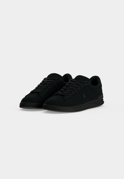 Ζευγάρι μαύρα χαμηλά sneakers με κορδόνια και διακριτική σήμανση Polo στο πλάι και στη σόλα, εμφανιζόμενα σε απλό ανοιχτό φόντο.