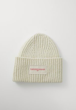 Knit beanie krēmkrāsā ar vertikālām ribām, ar locītu aproci un taisnstūra formas balto plāksni ar sarkano "tommy jeans" logotipu.