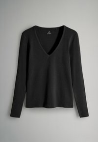 Černý dlouhý rukáv, žebrovaný pletený top s hlubokým véčkovým výstřihem, rovný lem a slim fit, vystavený na neutrálním šedém pozadí.