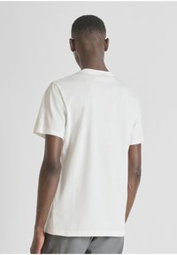 Camiseta de algodón blanca con mangas cortas y cuello redondo, que presenta una textura suave y un corte recto en el dobladillo.
