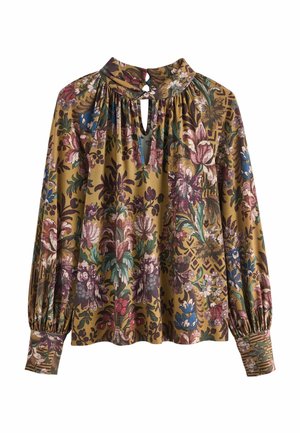 Blouse à manches longues à motifs floraux sur fond moutarde, col haut avec fente et fermeture par bouton, tissu froncé au niveau du col et des poignets.