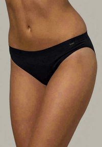 Melnas bikini apakšda, kas izgatavota no gludas, stiepjamas materiāla. Tam ir zemas vidukļa dizains ar minimālu pārklājumu un mazu logotipa akcentu uz jostasvietas.