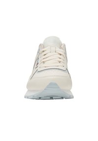 Zapatilla color crema con una mezcla de cuero y tela, que presenta un cuello acolchado, diseño con cordones y una suela texturizada en azul claro.