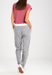 Gråmelerade joggingbyxor med elastisk vit midja, parat med en kortärmad rosa topp. Material i bomullsblandning, avslappnad passform.