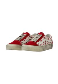Un paio di sneakers basse con la parte anteriore in suede rosso, lati bianchi decorati con stelle rosse, lacci bianchi e suole in gomma beige usurate.
