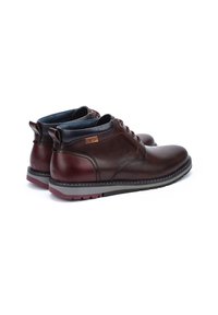 Brown leather ankle boots with a smooth finish, gray rubber sole, and burgundy accents. Features laces and a padded collar for comfort.