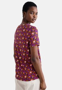 Top cu mânecă scurtă, floral, în nuanțe vibrante de roz, portocaliu și mov, cu guler rotund. Are un design cu model și o croială lejeră.