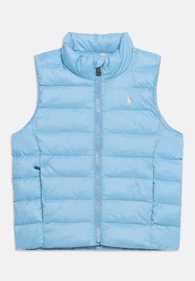 Ανοιχτό μπλε αμάντικο καπιτονέ γιλέκο με ψηλό γιακά, φερμουάρ μπροστά και μικρό κίτρινο κεντημένο λογότυπο στο αριστερό στήθος.