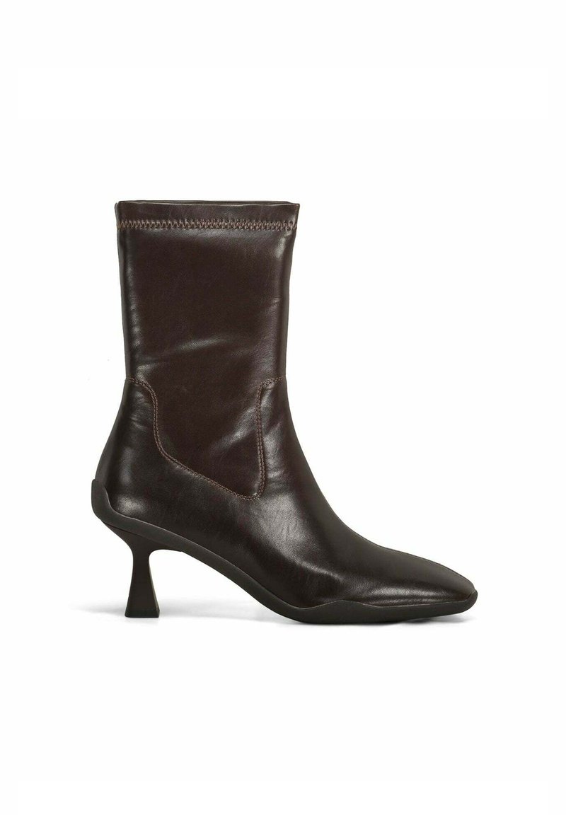 Bottine en cuir brun avec un bout pointu, un talon de hauteur intermédiaire, un design élastique et des coutures contrastantes le long du bord supérieur.