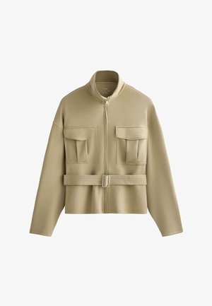 Beige Reißverschlussjacke mit Schnallen-Gürtel, zwei großen vorderen Klappentaschen und einem Stehkragen, dargestellt vor weißem Hintergrund.