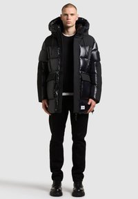 Musthave musta voodriga jope läikiva viimistlusega, kapuutsiga ja tõmblukuga. Omab suuri taskuid ja minimaliistlikku brändingut allääres. Sobilik mustade pükste ja jalatsitega.