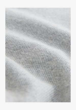 Tissu gris clair à texture douce, présentant un motif côtelé et des variations subtiles de teinte, soulignant son design tricoté.