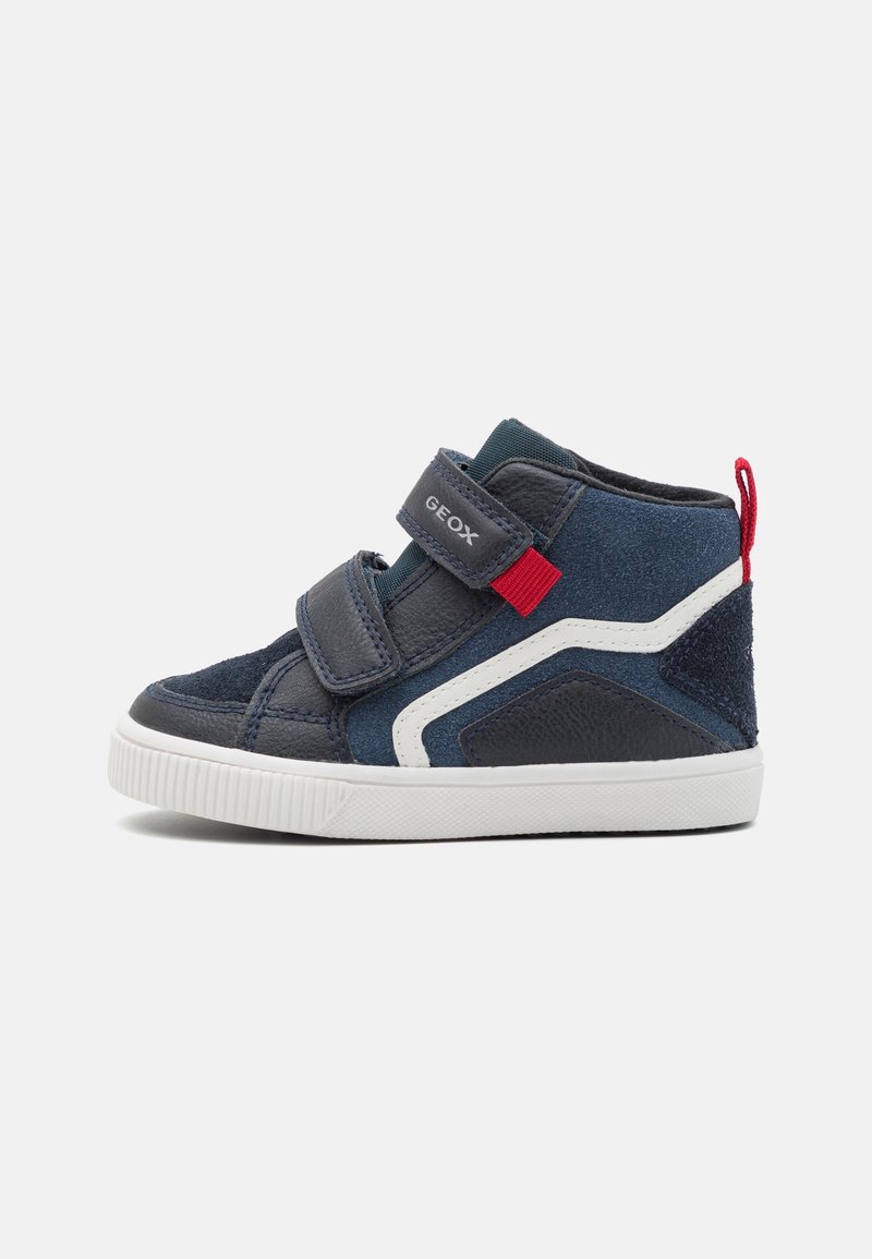 Baskets montantes bleu marine pour enfants, semelle blanche, deux bandes Velcro, languette rouge et détail en zigzag blanc le long du côté.