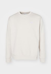 Cream-colored Nike sweatshirt with a round neck, ribbed cuffs and hem, and small white logo on the chest. Made from soft, textured fabric.