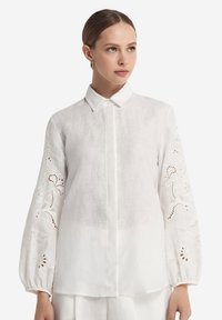 Witte linnen blouse met lange, geplooide mouwen en geborduurde bloemenpatronen. Voorzijde met knopen, klassieke kraag en een losse pasvorm.