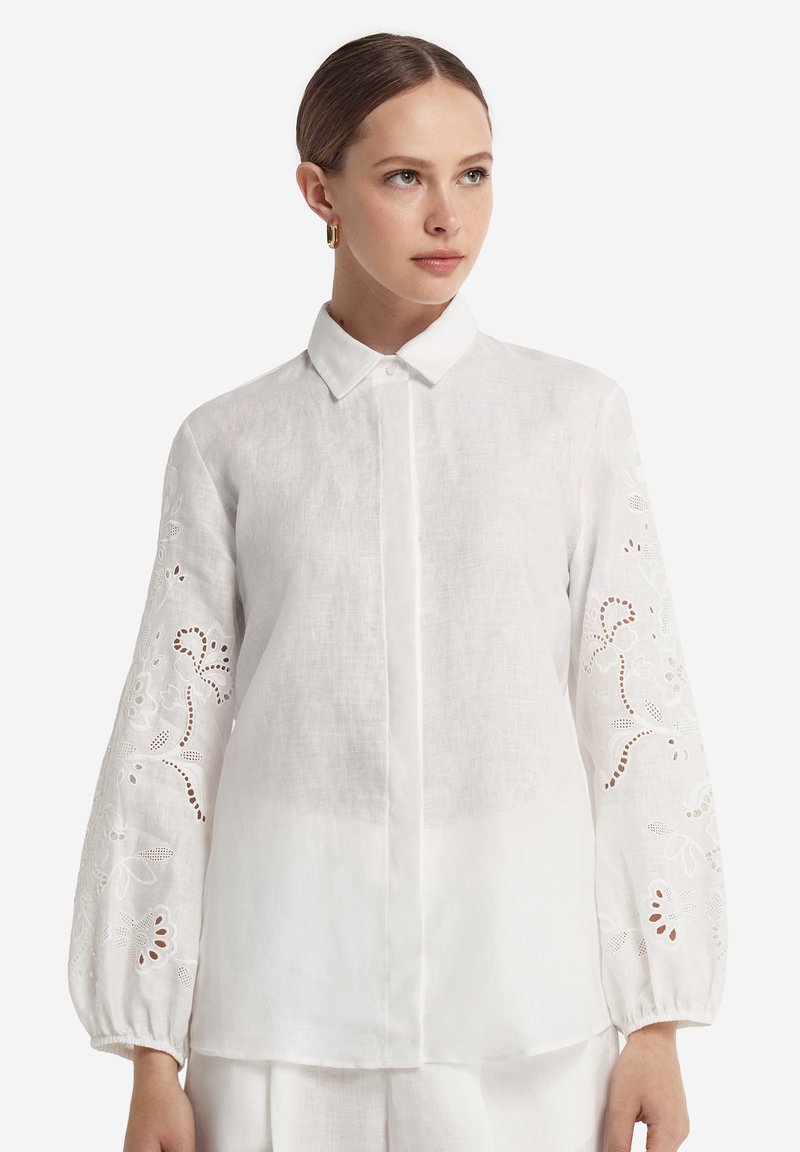 Witte linnen blouse met lange, geplooide mouwen en geborduurde bloemenpatronen. Voorzijde met knopen, klassieke kraag en een losse pasvorm.