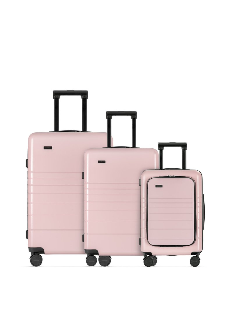 Tre valigie rigide rosa di dimensioni diverse, con linee testurizzate, manici neri e ruote per una facile mobilità.
