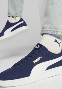 Marineblå sneakers med hvide detaljer og letvægtsmateriale. Har en glat tekstur, rund tå og signaturlogo på siden og tungen.