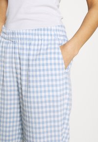 Blå och vit rutiga byxor med elastiskt midjeband och sidofickor. Mjukt tyg med en lätt, strukturerad yta.