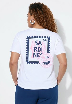 Vrouw met krullend haar die een wit T-shirt draagt met een ontwerp van een sardienenpostzegel en een roze Portimão Portugal poststempel op de rug.