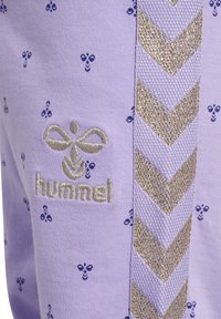 Sweatshirt violet clair avec de petits motifs d'abeilles navy, un logo brodé argenté et une bande en chevron avec des accents dorés sur le côté.