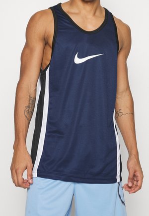 Personne musclée portant un débardeur de sport Nike bleu marine sans manches avec des bandes blanches sur les côtés et un short bleu clair.