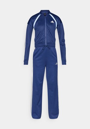 Marineblauer Trainingsanzug mit weißen Seitenstreifen, Reißverschlussjacke, Stehkragen und elastischem Bund. Auf Vorderseite und Hose ist das Adidas-Logo zu sehen.