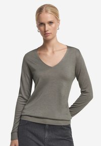 V-ringad långärmad tröja i olivgrön. Mjuk, strukturerad tyg med en figurnära design och ribbad nederkant. Enkel, mångsidig stil som passar bra för lager på lager.