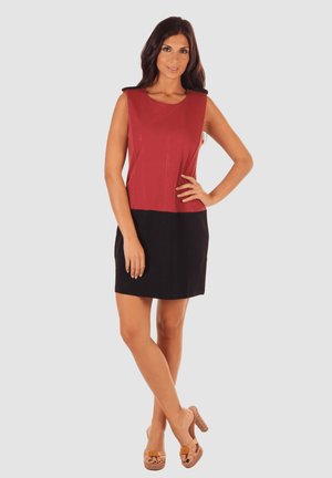 Vestido sin mangas con parte superior roja y falda negra, hecho de tejido suave. Presenta un escote redondo y un corte holgado, complementado con sandalias de cuña color tostado.