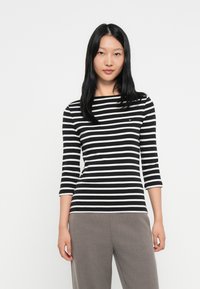 Svart og hvit stripete langermet topp med båtformet hals og trekvartlange ermer. Liten logo detalj på brystet.
