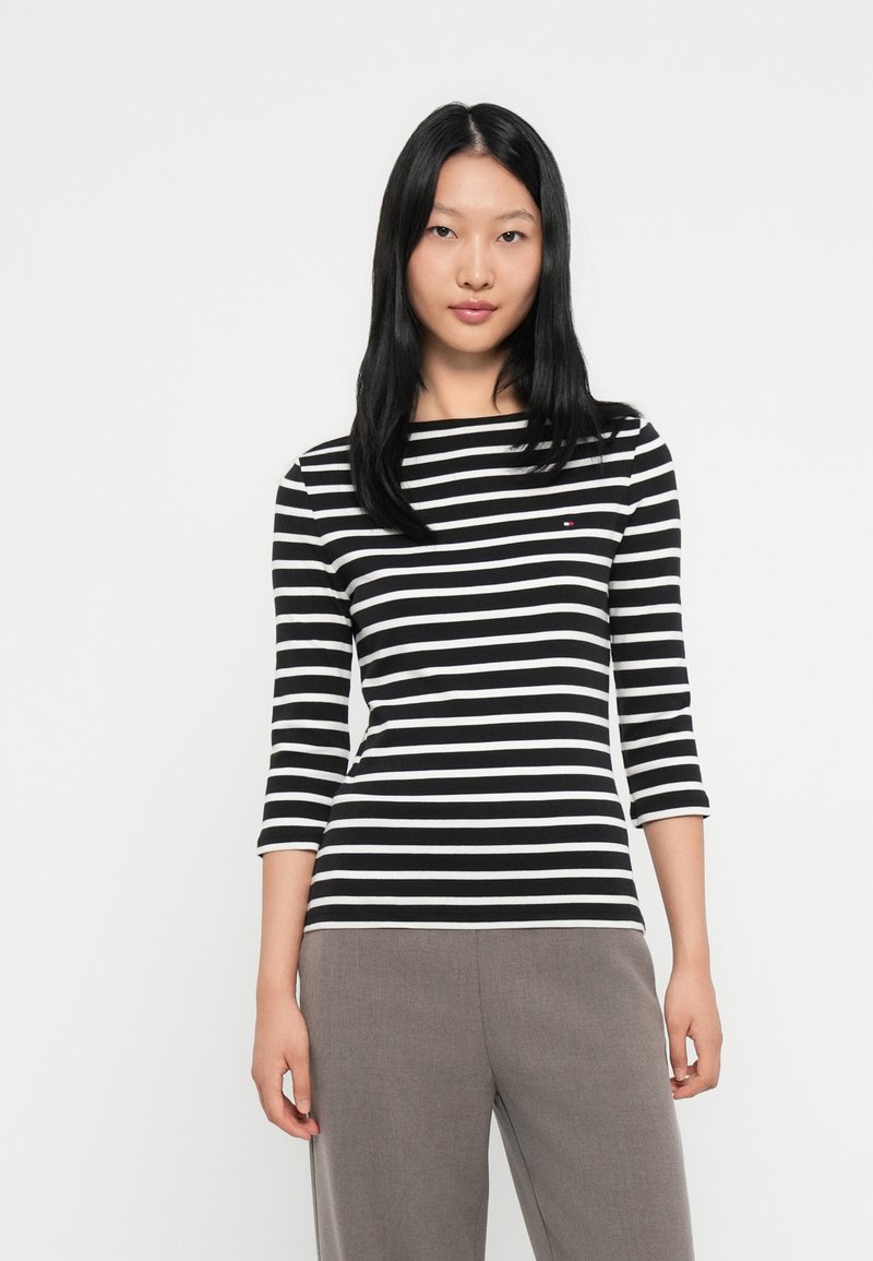 Svart og hvit stripete langermet topp med båtformet hals og trekvartlange ermer. Liten logo detalj på brystet.