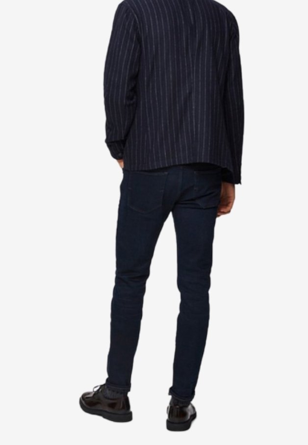 Blazer de rayas marineras con un corte relajado, combinado con jeans ajustados azul oscuro y zapatos negros, visto desde la parte trasera.