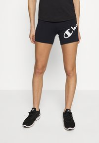Czarne sportowe szorty z białym logo z boku. Zestawione z czarnymi sneakersami na sznurówki. Prosty design, elastyczny materiał i dopasowany krój.