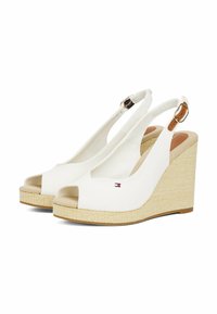 White slingback wedge shoes with a peep-toe design, fabric upper, textured espadrille wedge, and a small logo detail on the side.