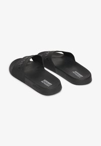 Zwarte schuimsandalen van rubber, met een brede, gegraveerde bovenband en een gestructureerde voetbed met "SUPERDRY" branding op de zool.