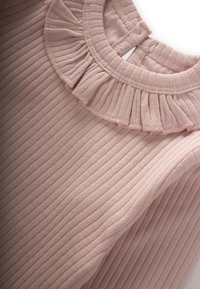 Top rosa pallido con texture a coste e un colletto arricciato. Presenta un design semplice con scollatura rotonda e chiusura con bottone sul retro.